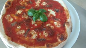Pizza de anchoas con pesto y tomates secados al sol y pistachos