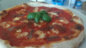 Pizza de anchoas con pesto y tomates secados al sol y pistachos