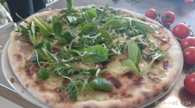 Pizza con pesto de oliva y almendra rúcula y Grana