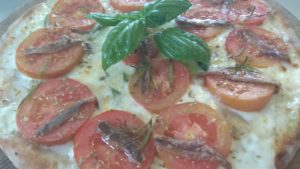 Pizza com Mozzarella Cereais com anchovas e fatias de tomate