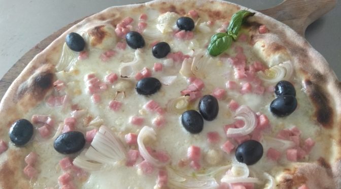 La pizza con jamón de mozzarella cebollas y las aceitunas