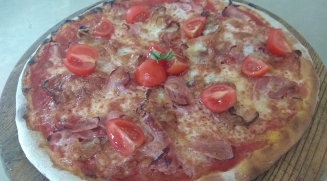 Pizza con tocino, jamón y tomates cherry